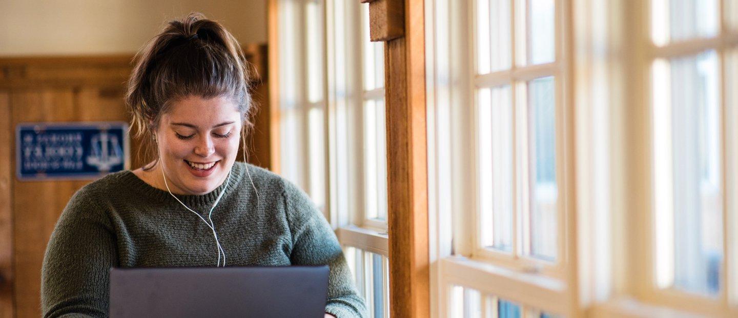 woman wearing headphones looking down at an open laptop